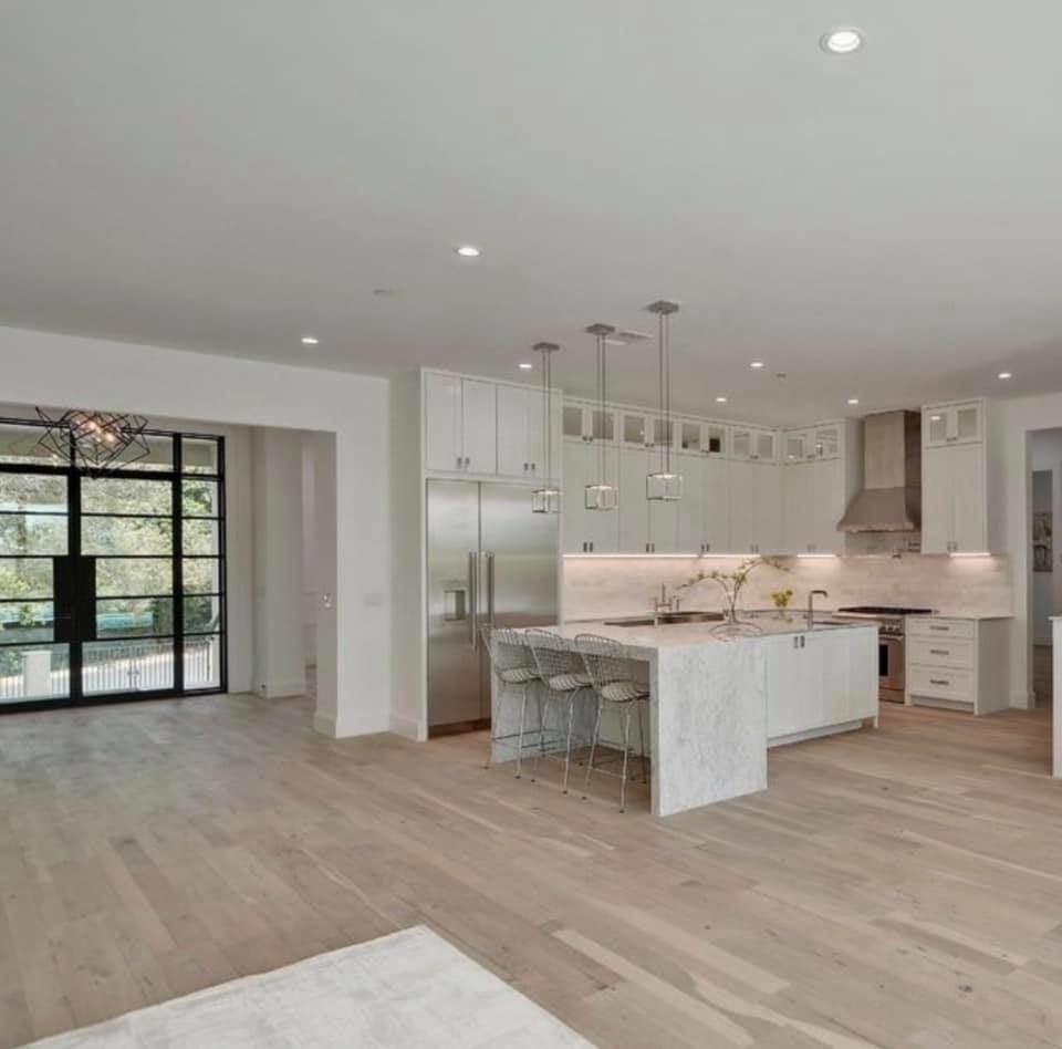 Inspiration for a mid-sized transitional l-shaped medium tone wood floor and brown floor eat-in kitchen remodel with a farmhouse sink, shaker cabinets, white cabinets, marble countertops, gray backsplash, stainless steel appliances, an island and gray countertops