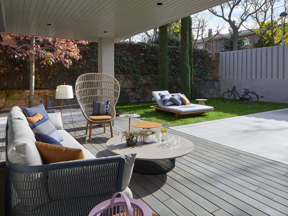 Design ideas for a contemporary backyard deck in Barcelona with a roof extension.