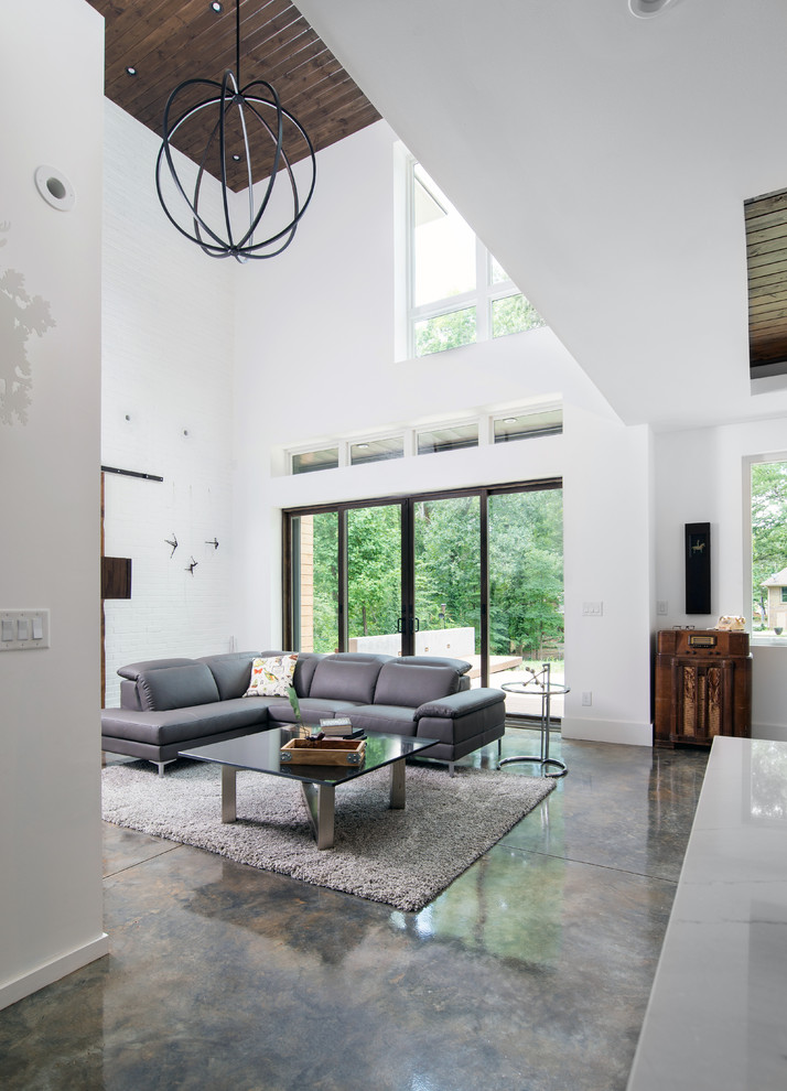 This is an example of a mid-sized modern formal open concept living room in Atlanta with white walls, concrete floors and no tv.
