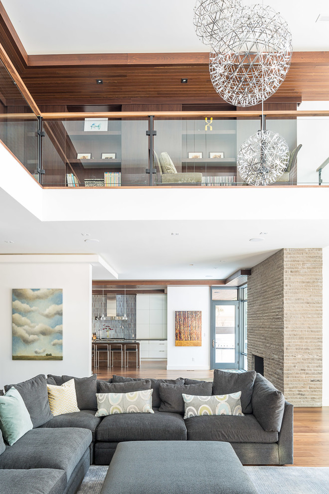 This is an example of a contemporary open concept living room in Toronto with white walls and medium hardwood floors.