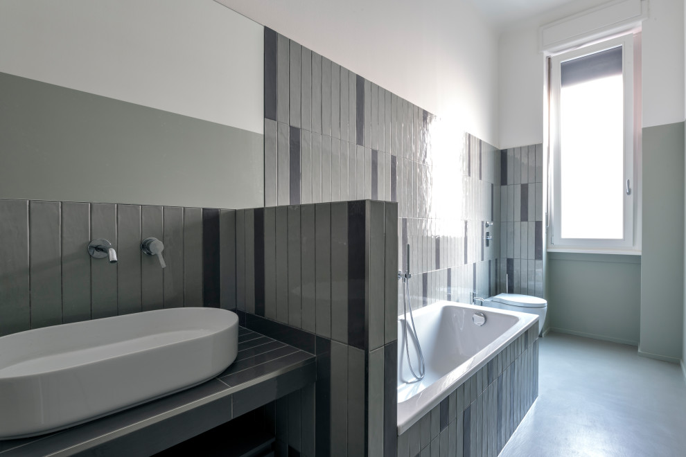 Inspiration for a mid-sized modern master bathroom in Milan with flat-panel cabinets, grey cabinets, a drop-in tub, a two-piece toilet, green tile, porcelain tile, green walls, concrete floors, a vessel sink, tile benchtops, grey floor, green benchtops, a single vanity and a floating vanity.