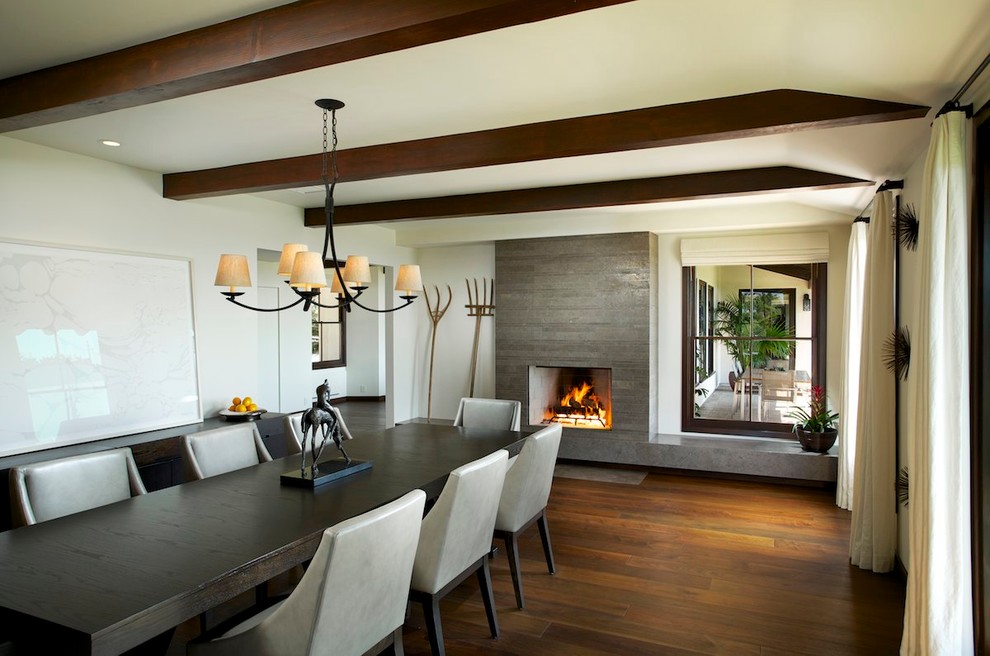 Contemporary dining room in Los Angeles with white walls, dark hardwood floors and a standard fireplace.