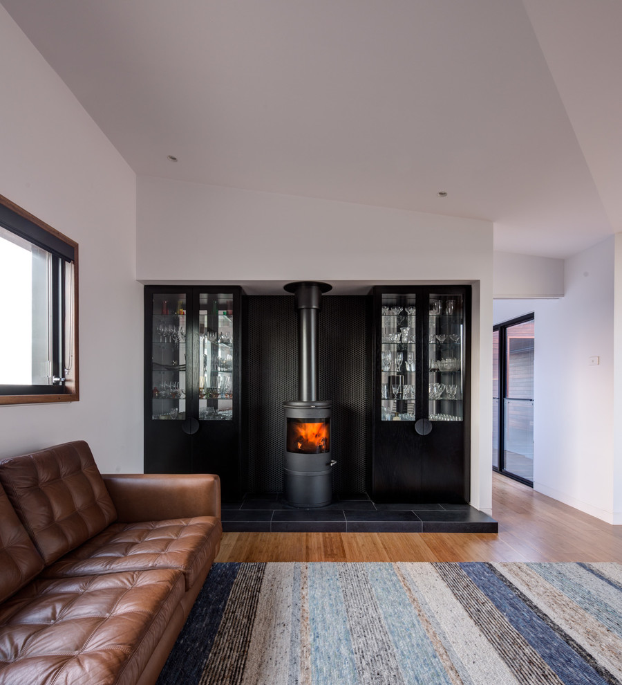 This is an example of a mid-sized modern open concept living room in Melbourne with white walls, bamboo floors, a wood stove, a tile fireplace surround and no tv.