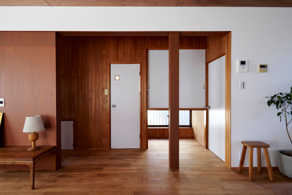 Aménagement d'un couloir de taille moyenne avec un mur blanc, un sol en bois brun, un sol marron, un plafond en bois et du lambris de bois.