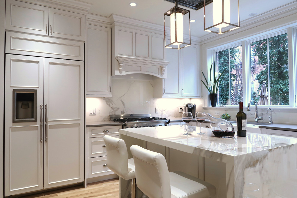 Enclosed kitchen - small transitional u-shaped light wood floor and brown floor enclosed kitchen idea with a farmhouse sink, recessed-panel cabinets, white cabinets, quartz countertops, white backsplash, stone slab backsplash, stainless steel appliances, an island and white countertops