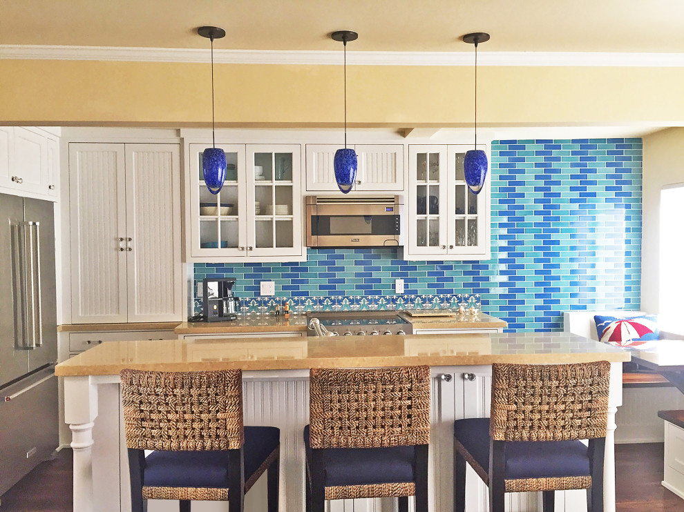 Inspiration for a small beach style galley eat-in kitchen in Other with beaded inset cabinets, white cabinets, quartz benchtops, blue splashback, subway tile splashback, stainless steel appliances, medium hardwood floors, with island, brown floor and beige benchtop.