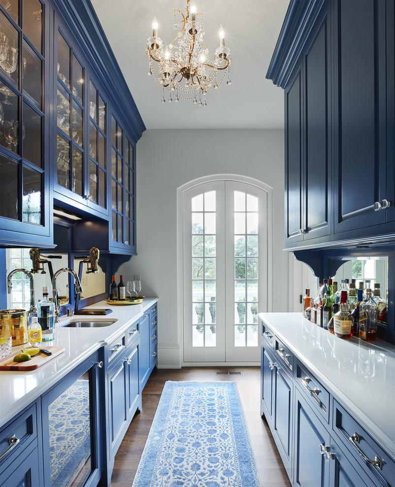 Photo of a traditional galley wet bar in Minneapolis with an undermount sink, raised-panel cabinets, blue cabinets, dark hardwood floors and brown floor.