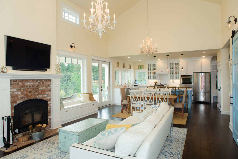 Mid-sized country open concept living room in Portland with white walls, dark hardwood floors, a standard fireplace, a brick fireplace surround and a wall-mounted tv.