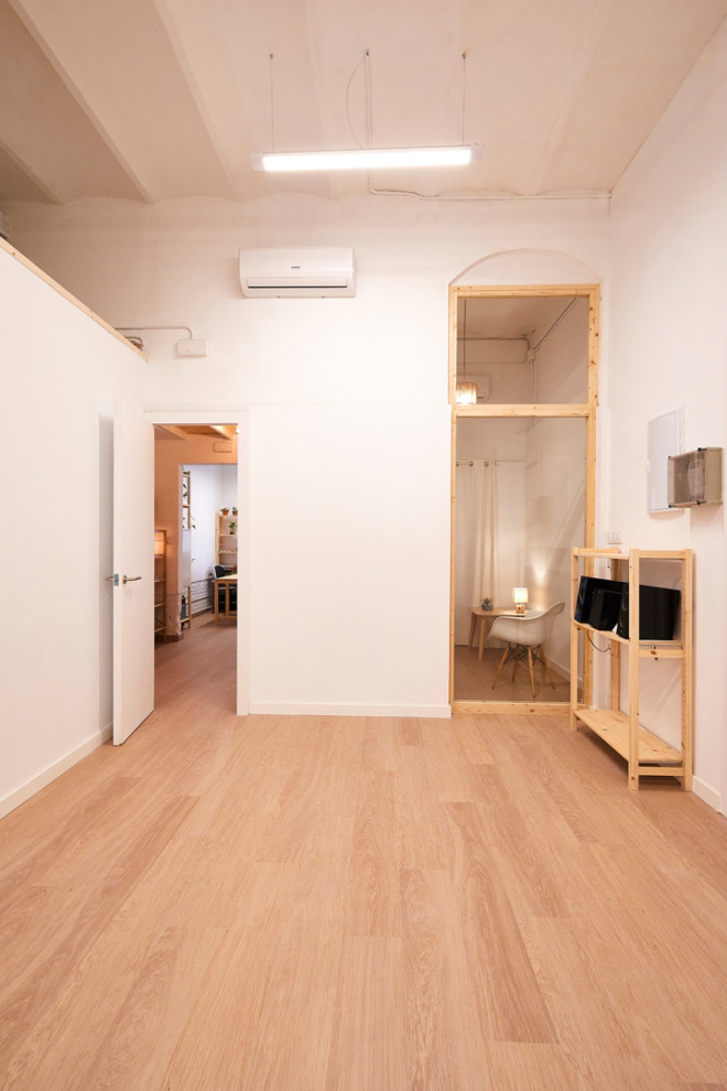 Photo of a small scandinavian home yoga studio in Barcelona with white walls, light hardwood flooring, beige floors and a vaulted ceiling.