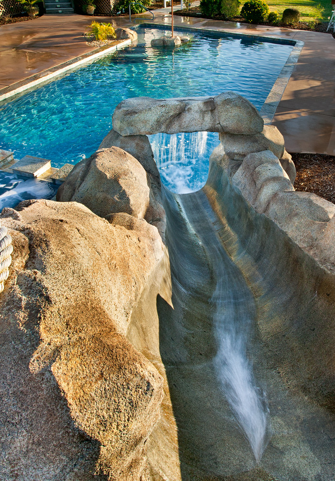 Inspiration for a mid-sized tropical backyard rectangular pool in San Diego with a water slide and concrete slab.