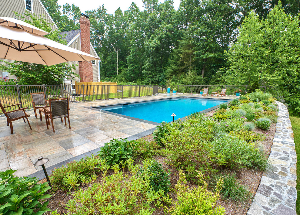 This is an example of a mid-sized traditional side yard rectangular infinity pool in Boston with with a pool and natural stone pavers.
