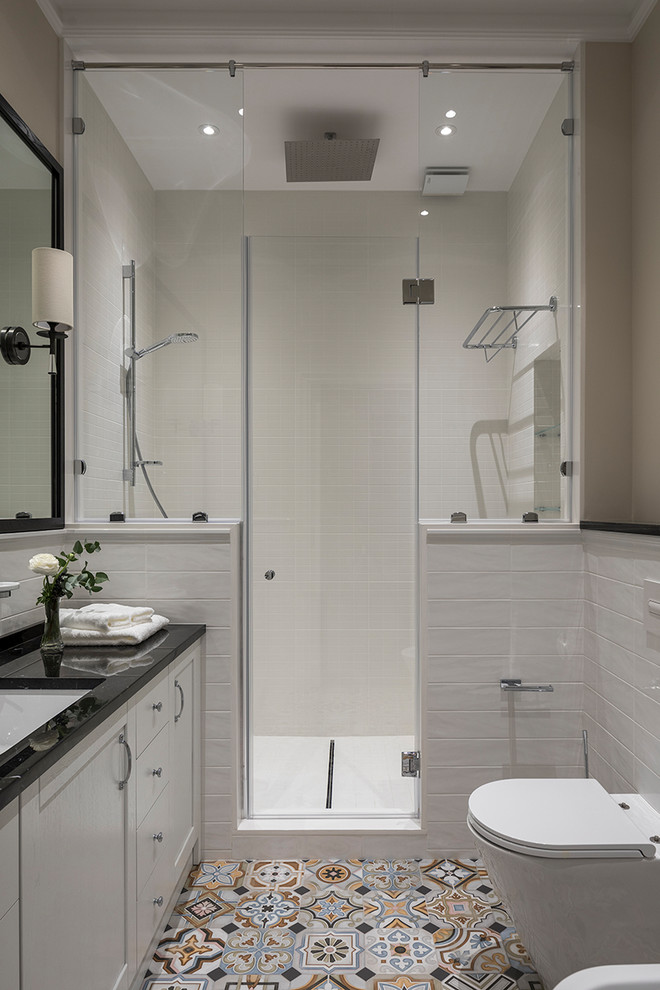 This is an example of a contemporary 3/4 bathroom in Moscow with white tile, recessed-panel cabinets, white cabinets, an alcove shower, a two-piece toilet, beige walls, an undermount sink, multi-coloured floor and a hinged shower door.
