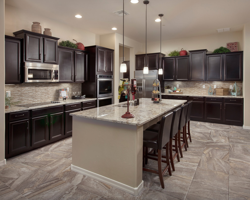 Design ideas for a traditional l-shaped kitchen in Phoenix with recessed-panel cabinets, stainless steel appliances and dark wood cabinets.