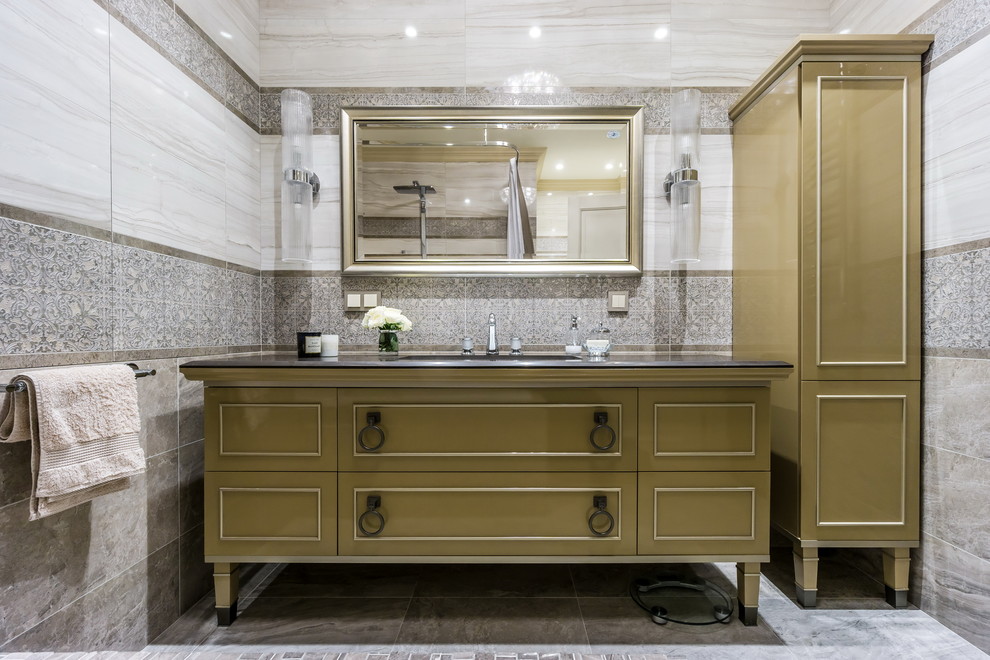Foto på ett mellanstort badrum, med luckor med profilerade fronter, ett badkar i en alkov, grå kakel, porslinskakel, grå väggar, klinkergolv i porslin, ett undermonterad handfat och bänkskiva i akrylsten