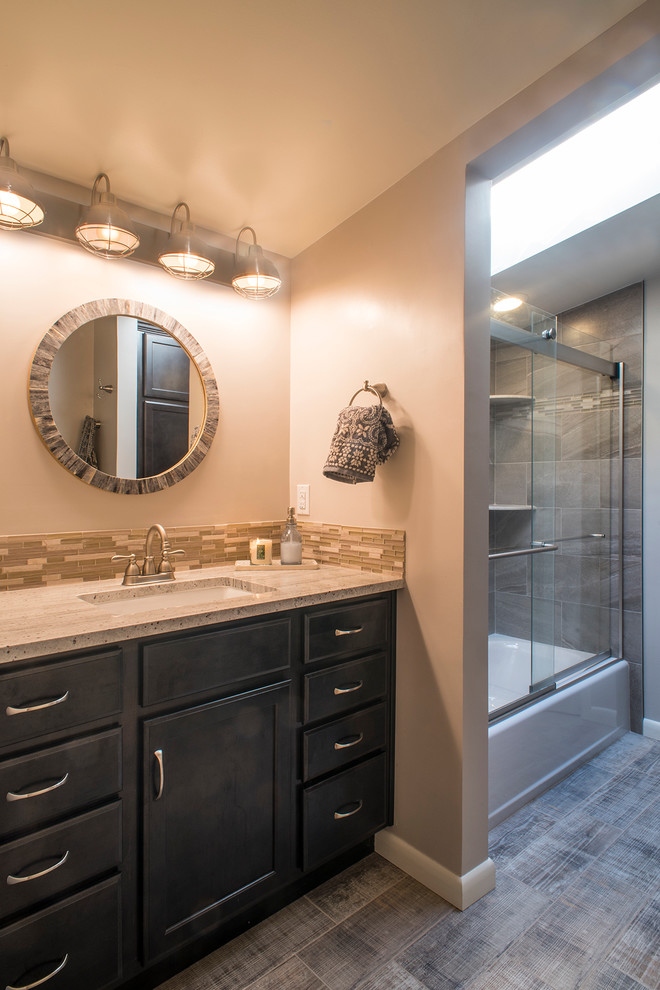 Inspiration for a mid-sized transitional kids bathroom in Denver with recessed-panel cabinets, dark wood cabinets, an alcove tub, an alcove shower, a two-piece toilet, gray tile, ceramic tile, grey walls, ceramic floors, an undermount sink and granite benchtops.
