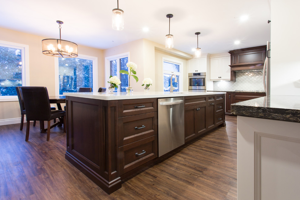 Inspiration for a large transitional l-shaped dark wood floor eat-in kitchen remodel in Orange County with a double-bowl sink, recessed-panel cabinets, white cabinets, granite countertops, gray backsplash, glass tile backsplash, stainless steel appliances and an island