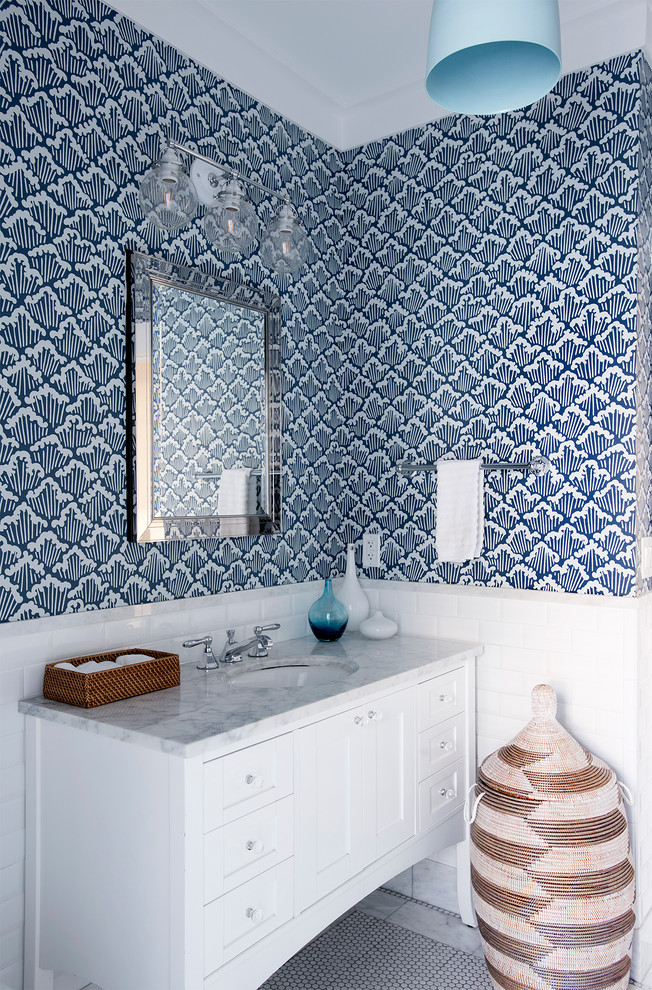 This is an example of a beach style powder room in New York with white cabinets, blue walls, mosaic tile floors, an undermount sink, multi-coloured floor, recessed-panel cabinets and grey benchtops.