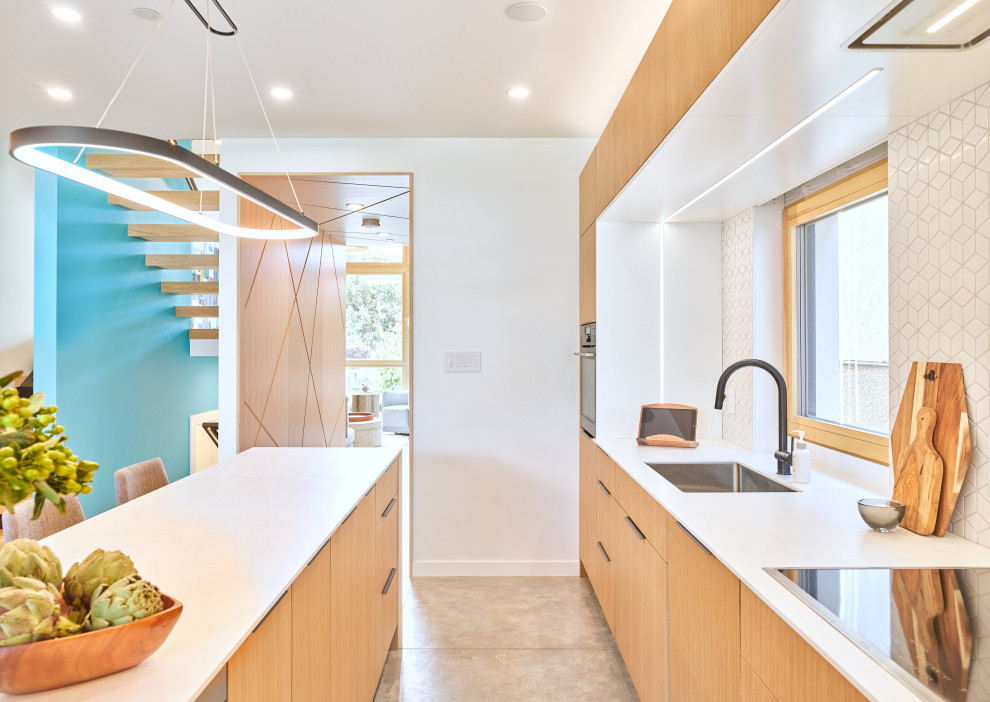 Foto på ett mellanstort funkis vit kök, med en undermonterad diskho, släta luckor, skåp i ljust trä, bänkskiva i kvarts, vitt stänkskydd, stänkskydd i mosaik, integrerade vitvaror, betonggolv, en köksö och grått golv