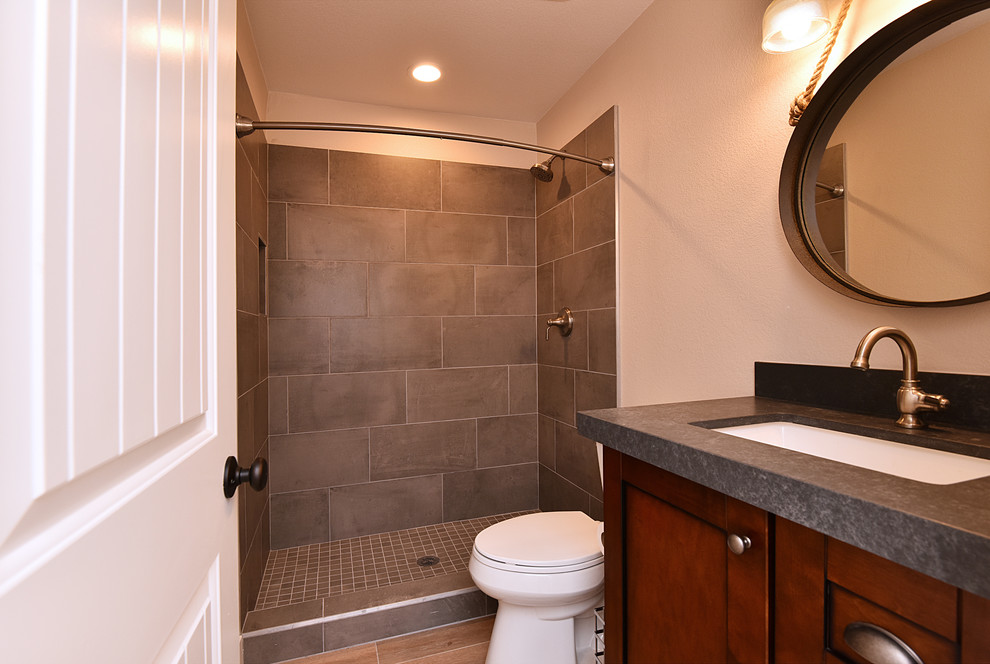 Inspiration for a mid-sized country 3/4 bathroom in Phoenix with shaker cabinets, dark wood cabinets, an alcove shower, a two-piece toilet, gray tile, porcelain tile, beige walls, light hardwood floors, an undermount sink, zinc benchtops, brown floor and a shower curtain.
