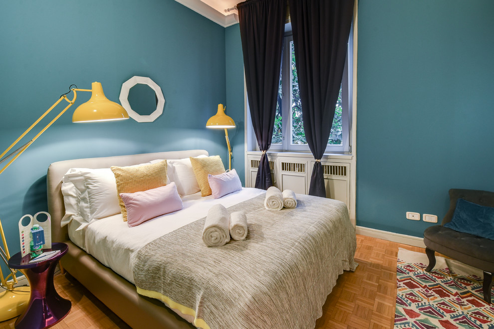 This is an example of a small modern guest bedroom in Milan with green walls and light hardwood floors.