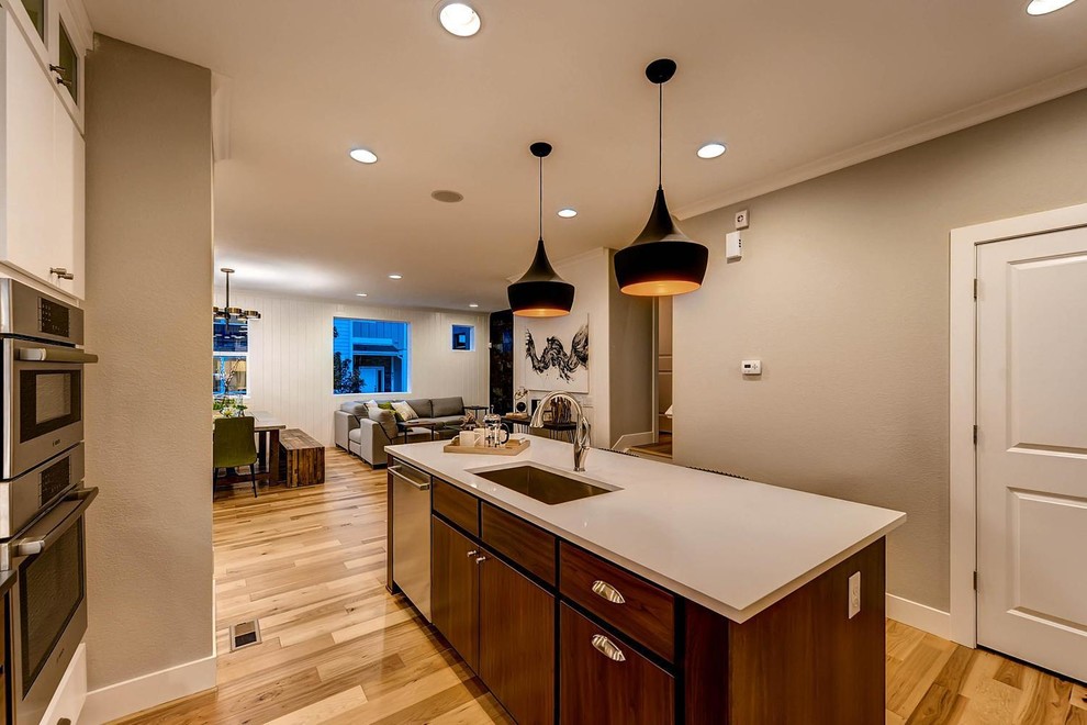 Mid-sized transitional l-shaped light wood floor eat-in kitchen photo in Denver with an undermount sink, flat-panel cabinets, dark wood cabinets, solid surface countertops, stainless steel appliances and an island