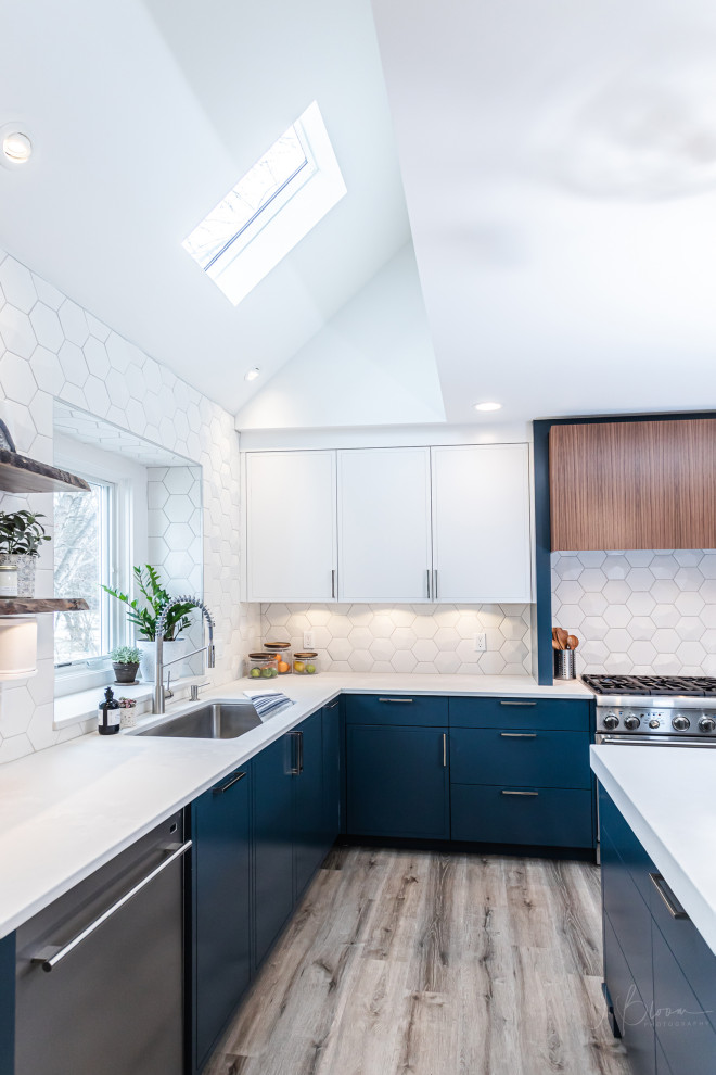 Inspiration for a mid-sized contemporary u-shaped eat-in kitchen in Omaha with a single-bowl sink, shaker cabinets, white cabinets, quartz benchtops, white splashback, ceramic splashback, stainless steel appliances, vinyl floors, with island, brown floor and grey benchtop.