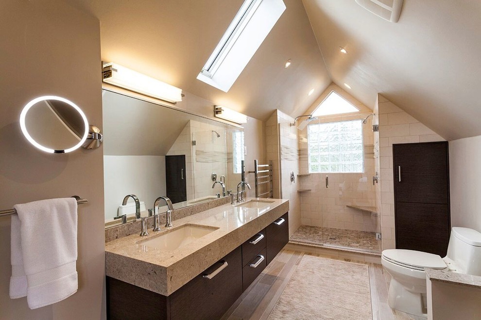 Modern master bathroom in Other with flat-panel cabinets, dark wood cabinets, a two-piece toilet, beige tile, pebble tile, beige walls, light hardwood floors and an undermount sink.