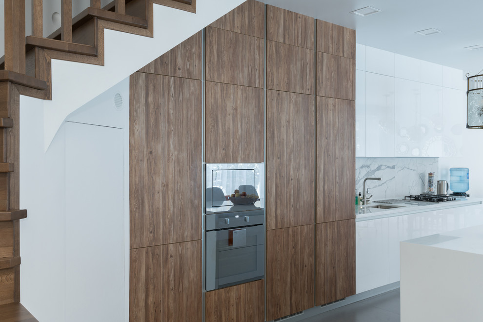 This is an example of a large contemporary single-wall open plan kitchen in Moscow with an integrated sink, flat-panel cabinets, white cabinets, quartz benchtops, white splashback, porcelain splashback, stainless steel appliances, porcelain floors, with island, grey floor and white benchtop.