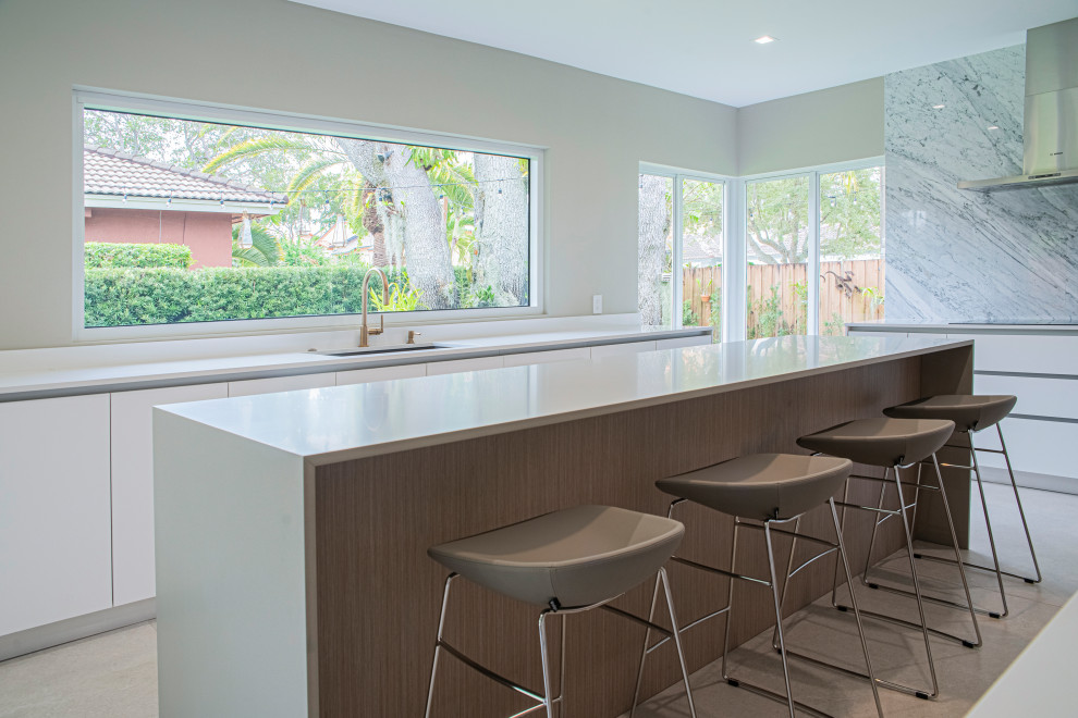 This is an example of a large modern u-shaped eat-in kitchen in Miami with an undermount sink, flat-panel cabinets, light wood cabinets, quartz benchtops, white splashback, marble splashback, panelled appliances, porcelain floors, with island, beige floor and white benchtop.