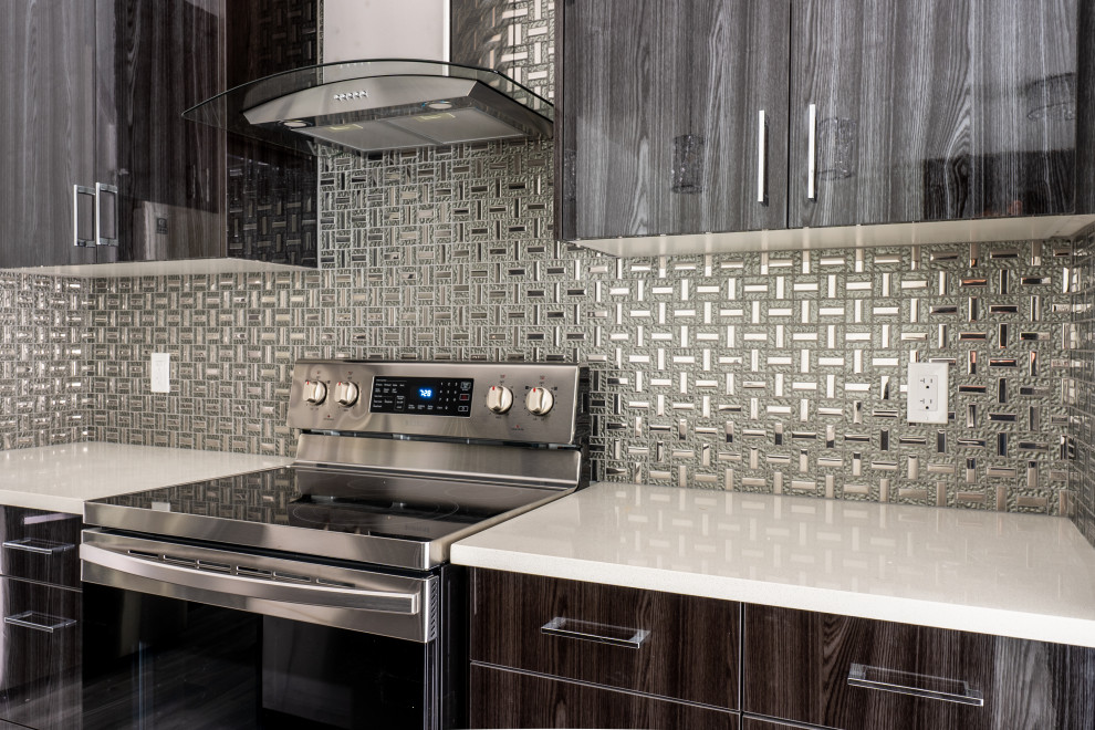 Example of a mid-sized trendy kitchen design in Edmonton with flat-panel cabinets, dark wood cabinets, metallic backsplash, stainless steel appliances and white countertops
