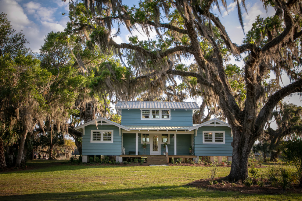 Mid-sized farmhouse two-story wood and clapboard exterior home photo in Tampa with a metal roof and a gray roof