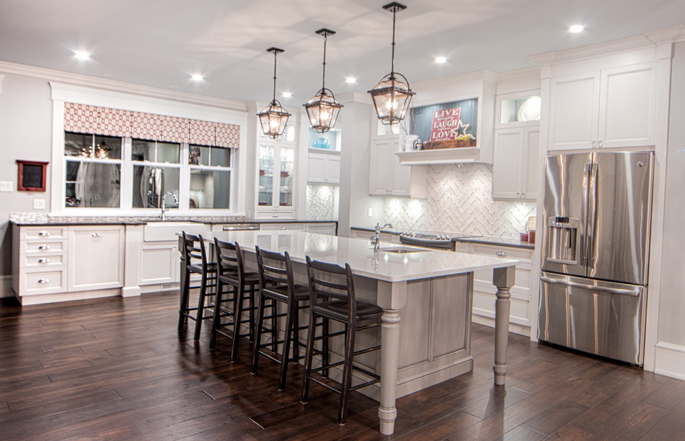 Kitchen - large transitional l-shaped dark wood floor kitchen idea in Toronto with a farmhouse sink, shaker cabinets, white cabinets, granite countertops, white backsplash, porcelain backsplash, stainless steel appliances and an island