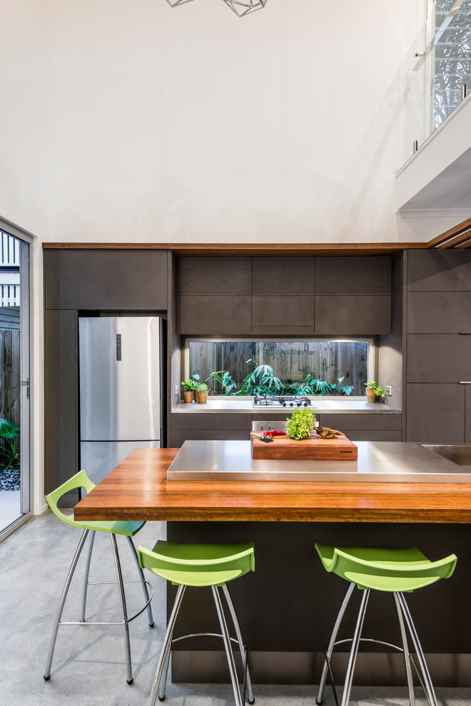 Inspiration for a small modern galley open plan kitchen in Brisbane with flat-panel cabinets, grey cabinets, stainless steel benchtops, glass sheet splashback, stainless steel appliances, concrete floors, with island and grey floor.