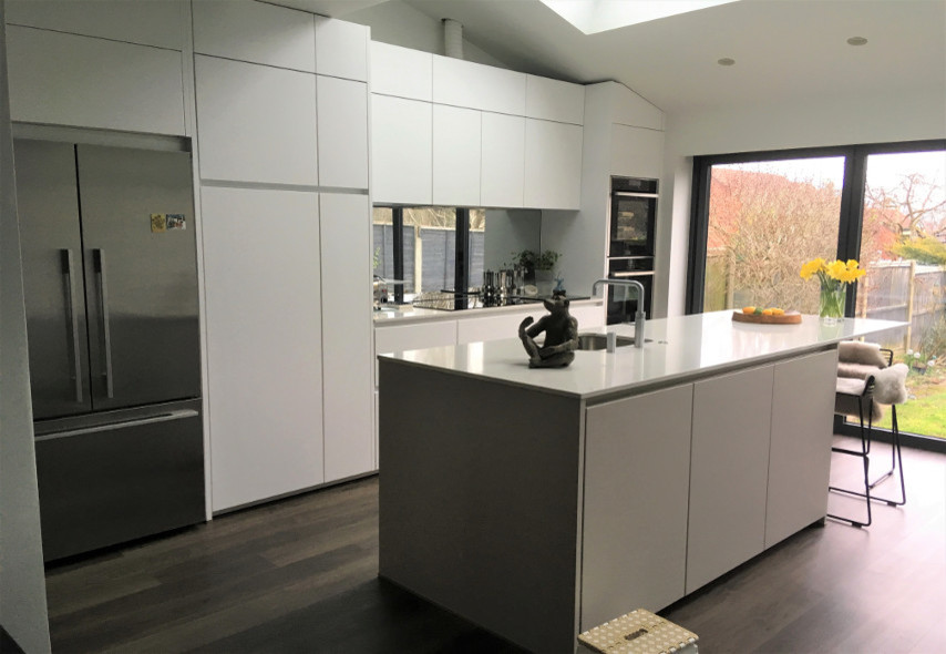 Photo of a modern kitchen in Hertfordshire with flat-panel cabinets, grey cabinets, mirror splashback and with island.