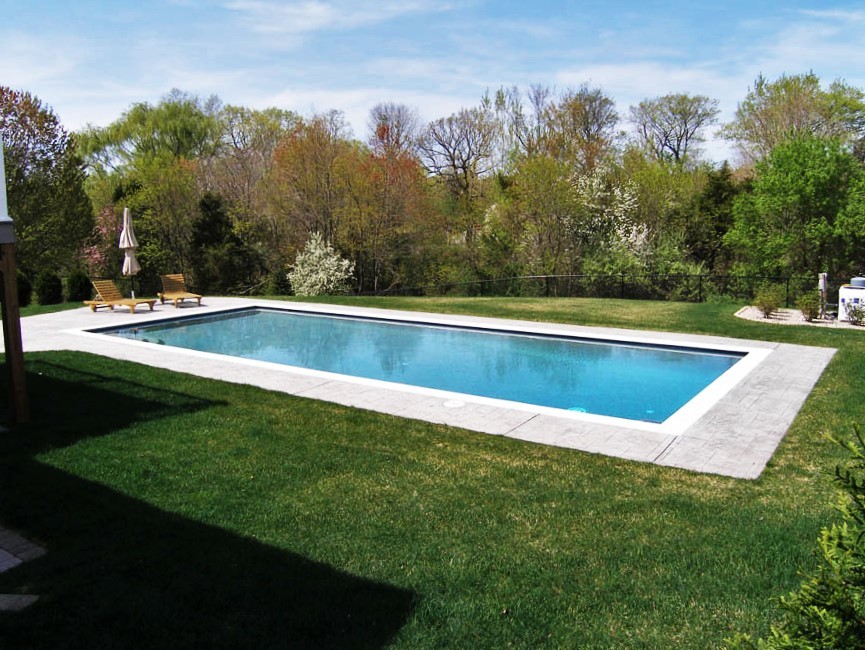 Photo of a large modern backyard custom-shaped pool in New York with a hot tub and stamped concrete.