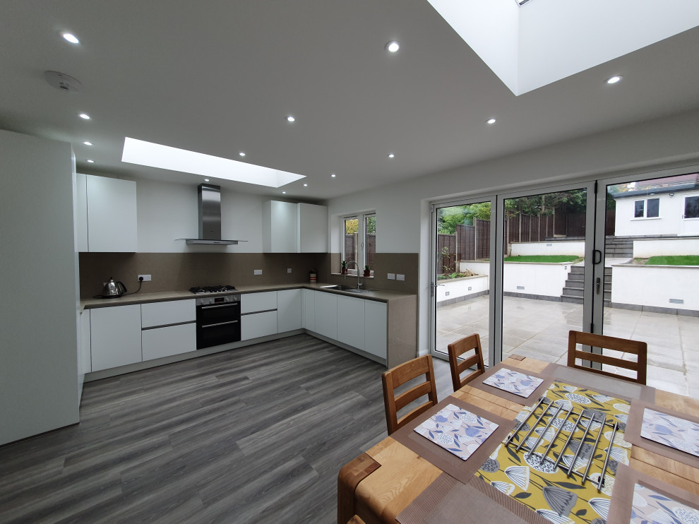 Immagine di una grande sala da pranzo aperta verso la cucina contemporanea con pareti bianche, pavimento in vinile e pavimento grigio