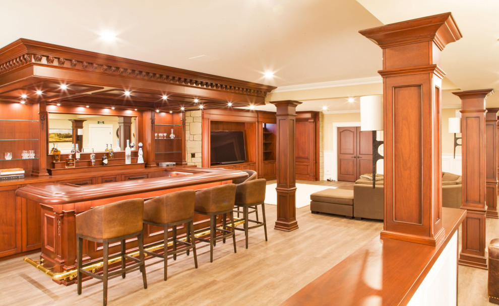 Foto de sótano con puerta abovedado clásico grande con bar en casa, paredes blancas, suelo de madera clara y suelo marrón