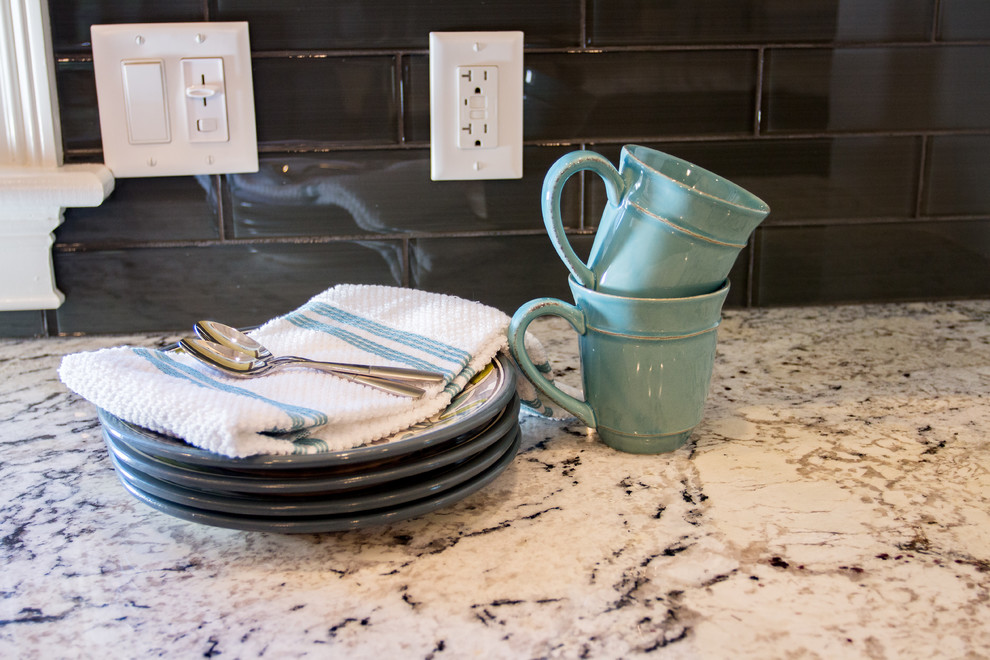 Transitional l-shaped dark wood floor kitchen photo in Providence with a farmhouse sink, raised-panel cabinets, granite countertops, gray backsplash, glass tile backsplash, paneled appliances and an island