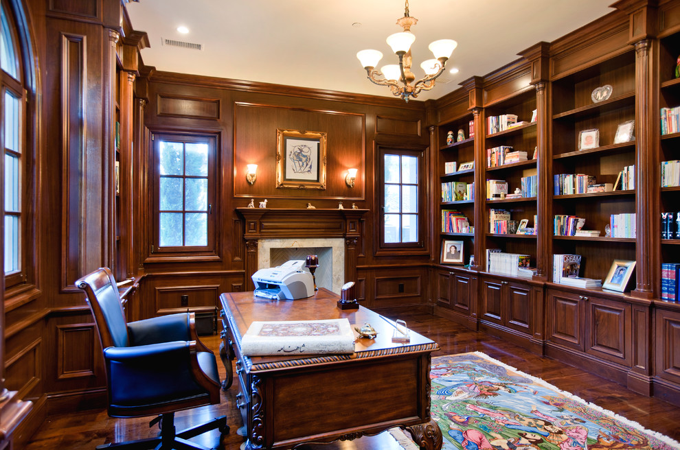 This is an example of a mid-sized mediterranean study room in Orange County with brown walls, dark hardwood floors, a standard fireplace and a freestanding desk.