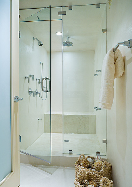 This is an example of a large contemporary wet room bathroom in New York with flat-panel cabinets, medium wood cabinets, a one-piece toilet, white tile, limestone, white walls, limestone floors, with a sauna, a vessel sink, limestone benchtops, white floor, a hinged shower door and white benchtops.