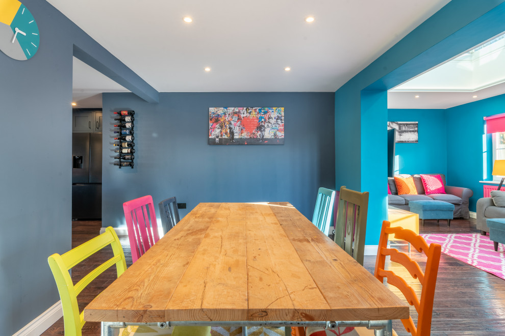 Exemple d'une salle à manger ouverte sur le salon tendance de taille moyenne avec un mur bleu, parquet foncé, un sol marron et éclairage.