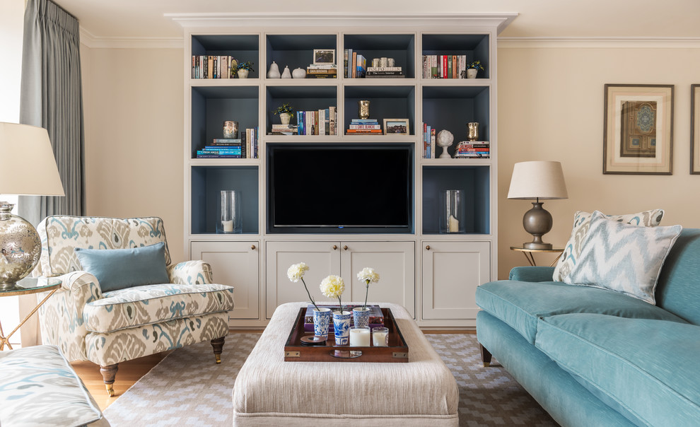 This is an example of a transitional living room in London with beige walls, light hardwood floors and a built-in media wall.