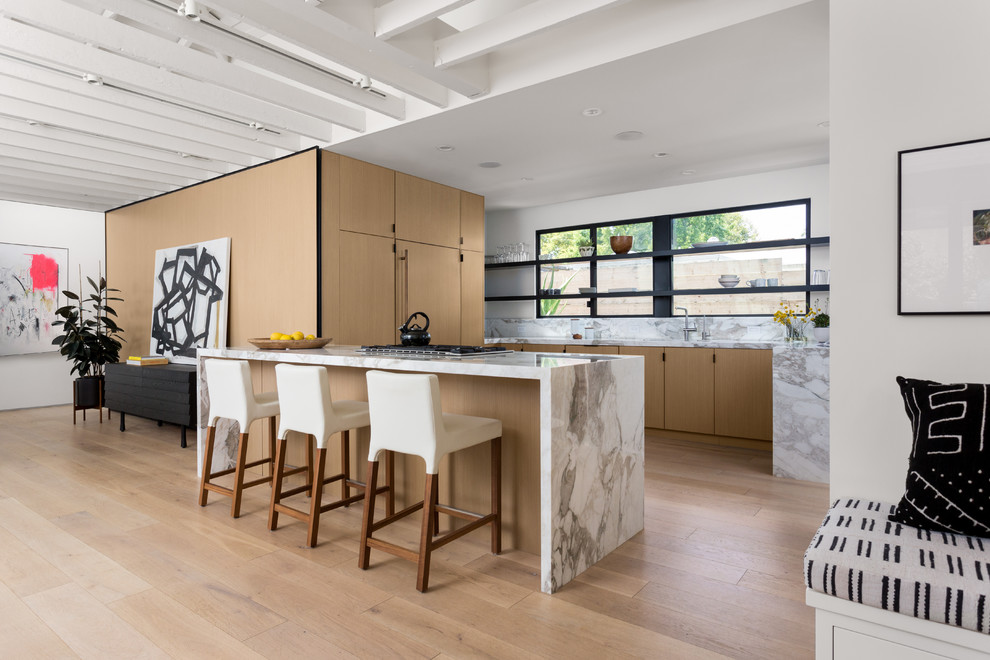 Inspiration for a mid-sized contemporary u-shaped open plan kitchen in Los Angeles with a double-bowl sink, flat-panel cabinets, light wood cabinets, marble benchtops, white splashback, marble splashback, panelled appliances, light hardwood floors, a peninsula and beige floor.