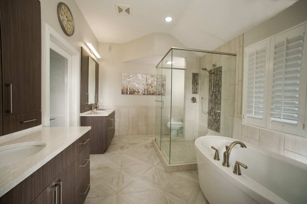 Design ideas for a mid-sized contemporary master bathroom in Wichita with flat-panel cabinets, brown cabinets, a freestanding tub, a two-piece toilet, beige tile, porcelain tile, beige walls, porcelain floors, an undermount sink, engineered quartz benchtops, beige floor, a hinged shower door, white benchtops, a niche, a double vanity and a built-in vanity.