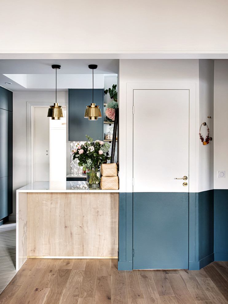 Mid-sized contemporary open plan kitchen in Paris with an undermount sink, beaded inset cabinets, blue cabinets, marble benchtops, grey splashback, terra-cotta splashback, panelled appliances, terra-cotta floors, with island, white floor and white benchtop.