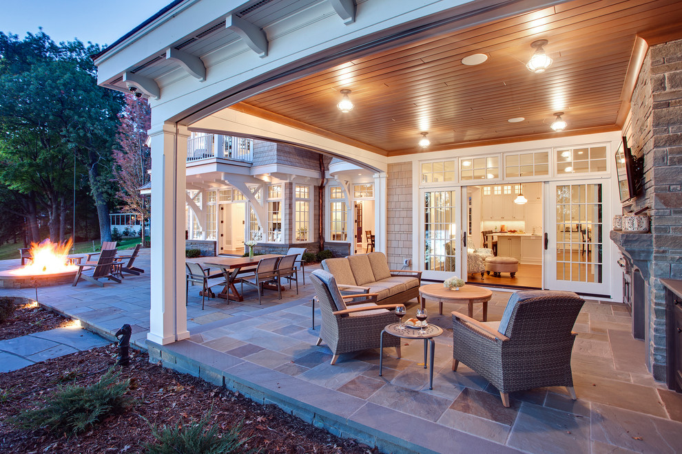 This is an example of a traditional backyard verandah in Minneapolis with natural stone pavers and a roof extension.