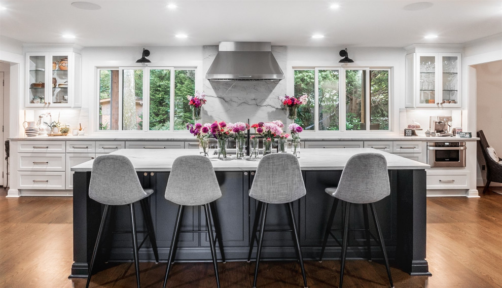 Large transitional single-wall eat-in kitchen in Atlanta with a single-bowl sink, shaker cabinets, white cabinets, quartzite benchtops, grey splashback, marble splashback, stainless steel appliances, medium hardwood floors, with island, brown floor and grey benchtop.