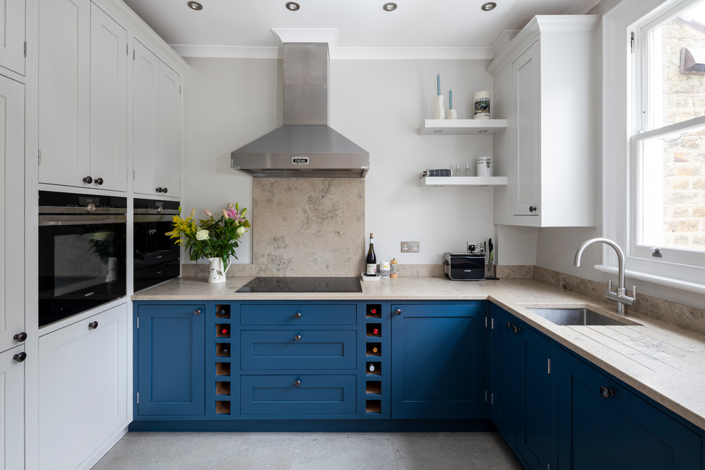 This is an example of a mid-sized traditional u-shaped kitchen in Dorset with an undermount sink, shaker cabinets, blue cabinets, limestone splashback, stainless steel appliances, no island, grey floor, beige splashback and beige benchtop.