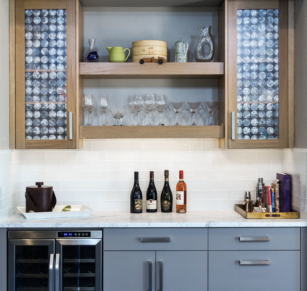 Inspiration for a large transitional galley home bar in Portland with flat-panel cabinets, grey cabinets, marble benchtops, white splashback, glass tile splashback and dark hardwood floors.