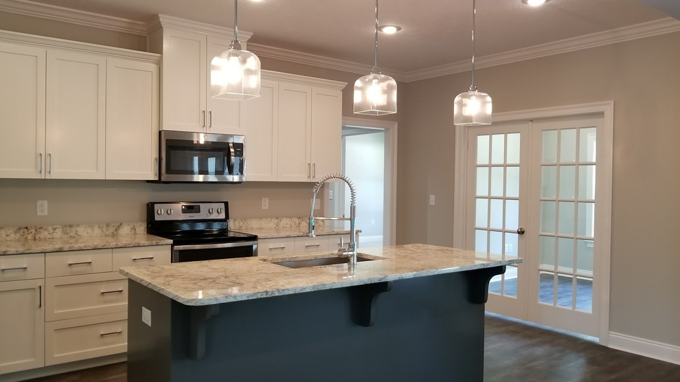 Design ideas for a mid-sized arts and crafts l-shaped open plan kitchen in Other with an undermount sink, shaker cabinets, white cabinets, granite benchtops, stainless steel appliances, vinyl floors, with island, multi-coloured floor and white benchtop.